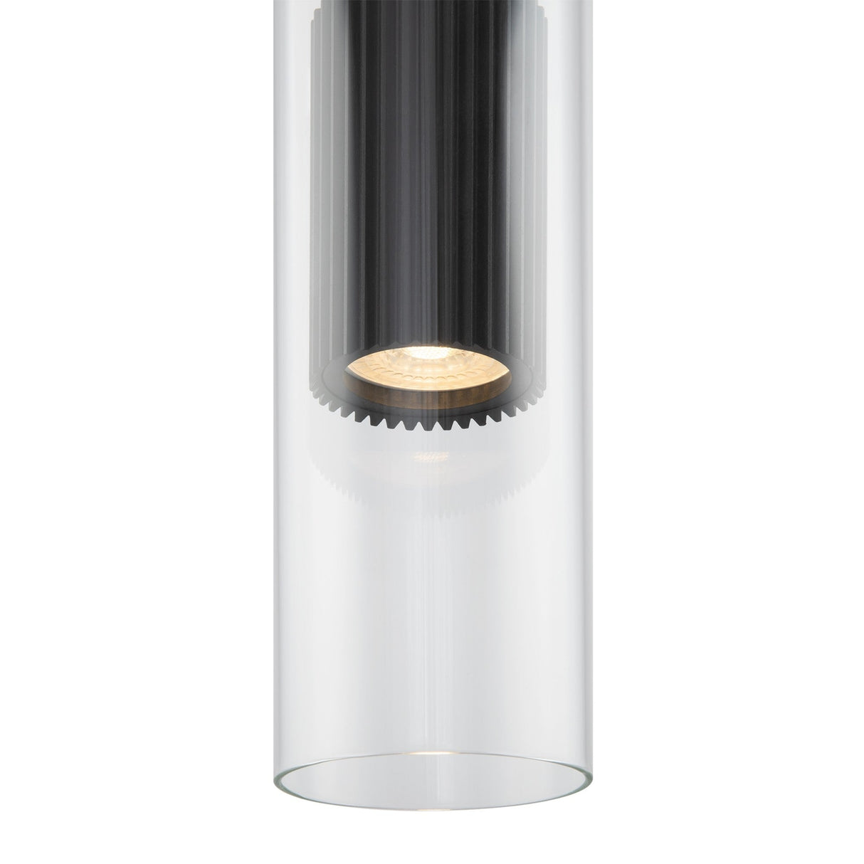 A close-up of the Dynamics Pendant Light showcases a modern cylindrical design with clear glass casing and a ribbed black interior around the bulb. It has a matte black finish, creating a warm, concentrated downward glow.
