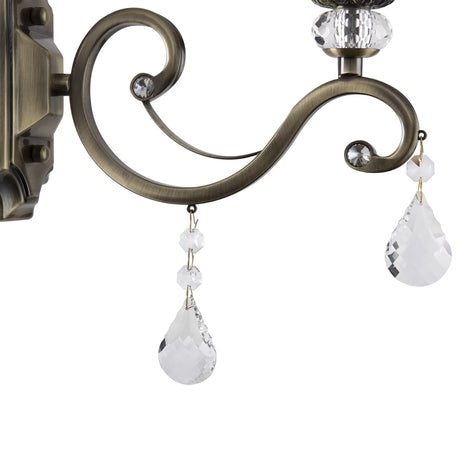 The Grace Classic Wall Light in bronze features elegant curves with small clear crystal accents and two larger teardrop ornaments, exuding a vintage aesthetic.