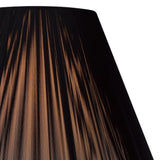 Close-up of the Elena 1 Light Crystal Floor Lamp - Black (Without Shade), showing warm light shining through vertical pleats in a black lampshade, creating striped patterns against a white background.