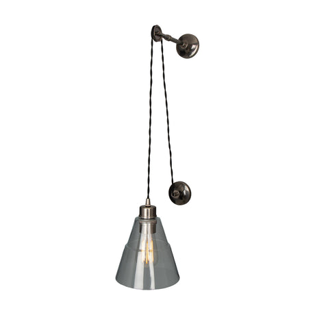 Elsoren Glass Wall Light with a clear cone glass shade on twisted black flex, suspended from an antique silver pulley wall fixture against a plain white background.