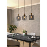Empoli Linear Pendant Light with three black wire-cage shades and brushed brass lampholders, shown suspended above a black dining table with exposed bulbs.