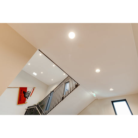 Erzeni LED Downlight 15cm in white recessed into an angled ceiling above a staircase, shown alongside similar round downlights lighting the landing.