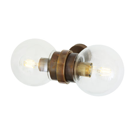 Eske Double Glass Globe Wall Light with two clear glass globes either side of a banded antique brass collar, each holding a visible E27 bulb, shown on a plain white background.