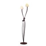 The Estilo 2 Light Floor Lamp in Brown & Black Oxide features a dark metal base and three curved stems, two with amber frosted glass shades resembling flower petals—ideal for soft ambient lighting.