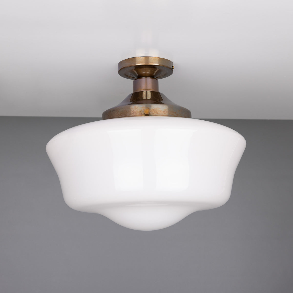 Ethrina Glass Semi Flush Ceiling Light with white opal schoolhouse-style shade and antique brass fitter and ceiling plate, shown against a plain grey background.
