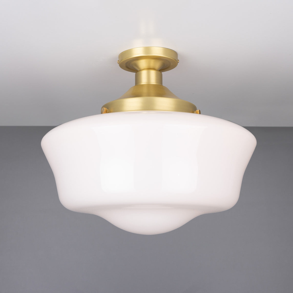 Ethrina Glass Semi Flush Ceiling Light with a white opal schoolhouse-style glass shade and satin brass fitter on a short stem, against a plain grey background.