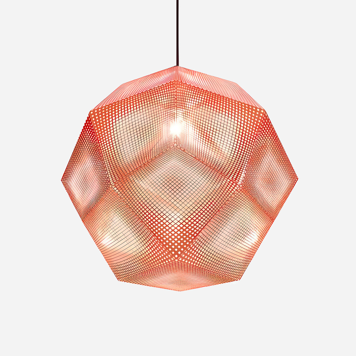 The Rango Large Pendant Light - Copper showcases a perforated dodecahedron design with a red surface, suspended by a black cord to cast a warm glow. Its acid-etching technique enhances the intricate, mesh-like effect against its white background.