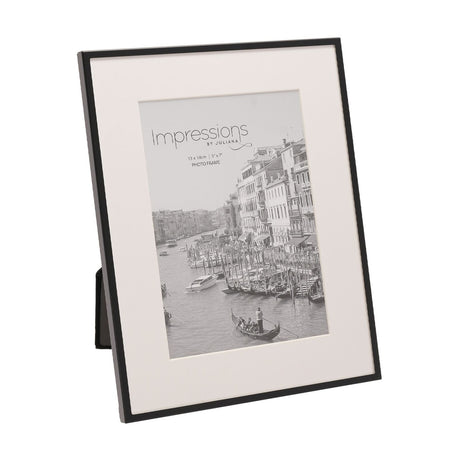 Matt black metal rectangular photo frame with a white mount holding a 7 x 5in sample print, shown at an angle on a plain white background.