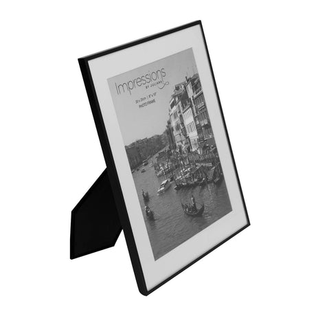 Matt black rectangular photo frame with white mount and fold-out stand, holding a 10 x 8in print, shown at an angle on a white background.