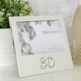 Silver aluminium 6x4in photo frame with raised 3D "30" below the picture, shown on a table beside a plant and candle.