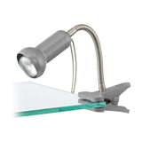 Fabio Clip On Lamp in silver, with a rounded spot head on a flexible steel gooseneck arm and a spring clip base, shown clipped to a glass shelf edge on a white background.
