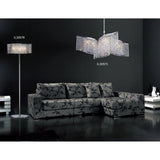 A modern living room features a black patterned sectional, glossy floor, and the Fabio 4 Light Crystal Floor Lamp - Chrome (Without Shade) on the left, paired with a matching chandelier. Dark walls and elegant lighting enhance the glamorous atmosphere.