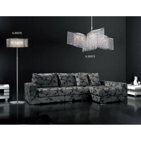A modern living room features a black patterned sectional, glossy floor, and the Fabio 4 Light Crystal Floor Lamp - Chrome (Without Shade) on the left, paired with a matching chandelier. Dark walls and elegant lighting enhance the glamorous atmosphere.