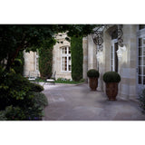 Fasvette Downward Outdoor Wall Light in white cast aluminium with glass panels, mounted on a stone façade beside French doors in a courtyard setting.