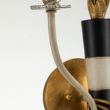 A detailed view of the Flambeau 2 Light Wall Light With Parchment Shade - Gold & Black highlights a vintage-style wall sconce, showcasing a brass base with an elegantly curved metal arm. This design features gold and black accents, complemented by candle-like light holders that bring an antique charm against a beige background, reflecting the festive elegance of Mardi Gras design.