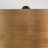 The Jackson 1 Light Table Lamp in Antiqued Silver with Gold Leaf is showcased against a wooden surface featuring smooth textures and natural grain patterns that evoke warmth. Atop this elegant display, the lamp's antiqued silver finish provides a sophisticated touch, enhancing the understated charm of the scene.