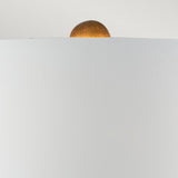 A minimalist photograph captures the top section of a round, golden element emerging from a sleek, light gray surface. This serene composition evokes modern design with an abstract touch, reminiscent of the Neo 1 Light Table Lamp in White & Gold.