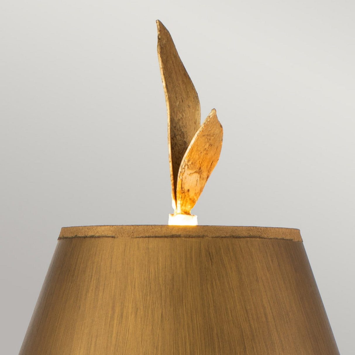 The Red Bell 1 Light Table Lamp features a sleek brown shade and embodies nature-inspired sophistication with decorative elements resembling two gold leaves, all set against a neutral backdrop.