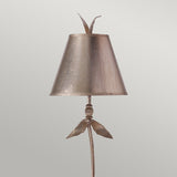 The Red Bell 1 Light Table Lamp features a decorative lamp design with a conical metallic shade in a Silver Leaf finish. It is adorned with a flower-like finial and leaf accents at the base, offering a brushed metal look that beautifully contrasts against a plain, neutral background.