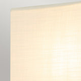 Close-up view of the Swirl 1 Light Small Wall Light - Gold Leaf featuring a softly lit, textured beige lampshade with a subtle swirl design against a gray background. The fabric displays a gentle grid pattern, beautifully diffusing the light.