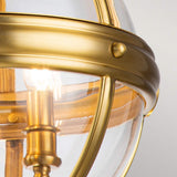 The Adams 3 Light Chandelier in burnished brass exudes elegance with its dome shape, metal bars, and visible screws. The clear glass allows the warm glow of the exposed bulbs to shine through, seamlessly blending classic Victorian design with modern flair.