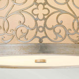 Detailed view of the Arabesque 2 Light Flush - Silver Leaf Patina, showcasing its intricate laser-cut scrollwork and swirling patterns with a floral motif on a beige background. The bottom of the fixture is elegantly finished with a Silver Leaf Patina ring.