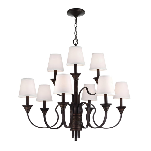 The Feiss Arbor Creek 9 Light Chandelier in bronze offers a stunning addition to transitional interiors, with its large black frame and chain supporting multiple curved arms. Each arm is adorned with a white lampshade, elegantly merging modern and traditional design elements.