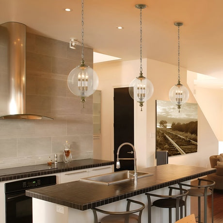 A contemporary kitchen features a sleek black countertop island complete with a built-in sink and chairs. Above it, an Argento 3 Light Chandelier in Oxidized Silver Leaf beautifully lights up the area. The room also includes a large wall photo of railroad tracks and a cozy seating area in the background.