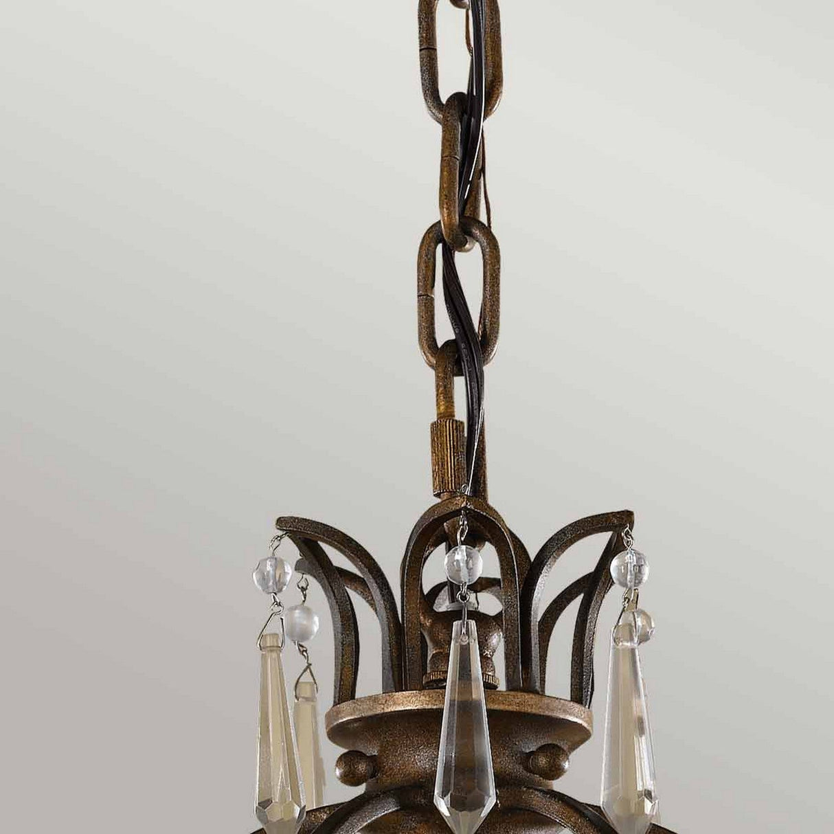 Close-up of the Bellini 1 Light Pendant Light - Oxidized Bronze/British Bronze, highlighting its oxidized bronze chain and frame. This stunning piece boasts antique quartz crystals elegantly suspended from curved metal branches, all set against a neutral backdrop.