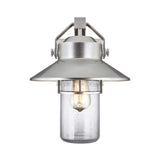 The Boynton 1 Light Outdoor Medium Wall Lantern, crafted in Painted Brushed Steel, features a modern design with a conical top and clear glass cylinder encasing a glowing bulb. Its sleek metal frame and nautical charm make it an ideal weather-resistant fixture for illuminating exterior spaces.