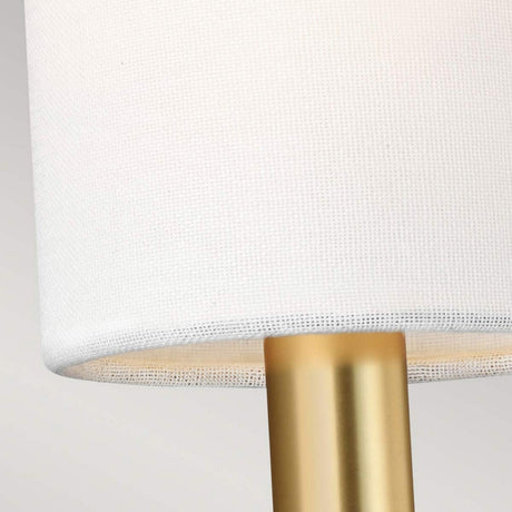 Close-up of a lamp featuring a white linen shade paired with a burnished brass base. The image emphasizes the texture of the shade and the elegant finish of the stand, evocative of the Brianna 1 Light Wall Light - Burnished Brass.