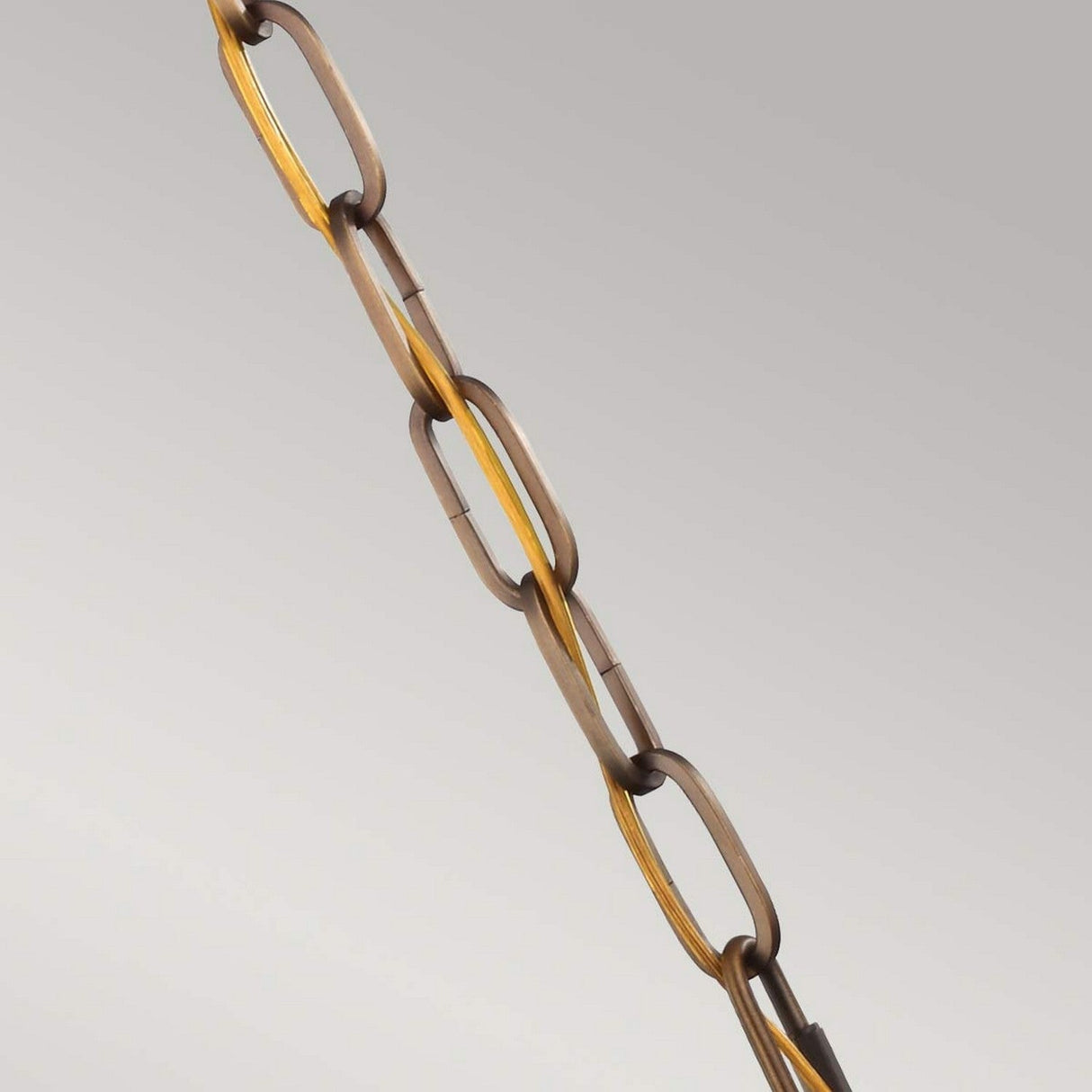 The Cadence 1 Light Mini Pendant in Dark Antique Brass and Matte Black, featuring a vertically hanging chain with oval links, exudes a vintage-industrial vibe against a light gray background. The slightly diagonal alignment of the chain evokes the charm of industrial lighting fixtures.