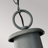 A close-up of the Chelsea Harbor 1 Light Outdoor Chain Pendant - Storm Cloud highlights its sleek, cylindrical design and gray metal finish. Featuring a circular ring at the top connected to a chain, this fixture radiates coastal industrial charm against a neutral backdrop.
