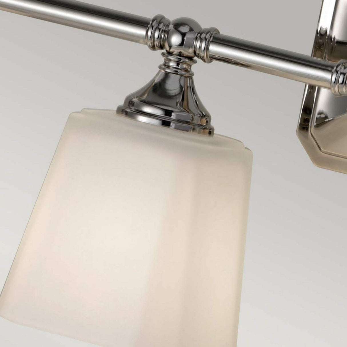Close-up of the Concord 4 Light Wall Light - Polished Chrome, featuring a sleek metallic frame and an opal-etched glass shade. The fixture is turned off, allowing its elegant design to stand out against a neutral background.