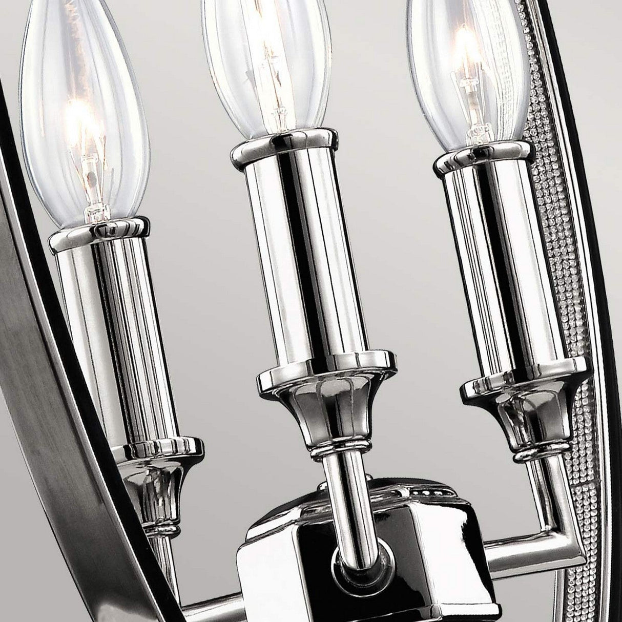 A close-up of the Corinne 3 Light Medium Chandelier in polished nickel exudes minimalist elegance with its three candle-shaped LED bulbs. Its sleek, metallic design stands out brilliantly against a neutral background.
