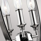 A close-up of the Corinne 3 Light Medium Chandelier in polished nickel exudes minimalist elegance with its three candle-shaped LED bulbs. Its sleek, metallic design stands out brilliantly against a neutral background.