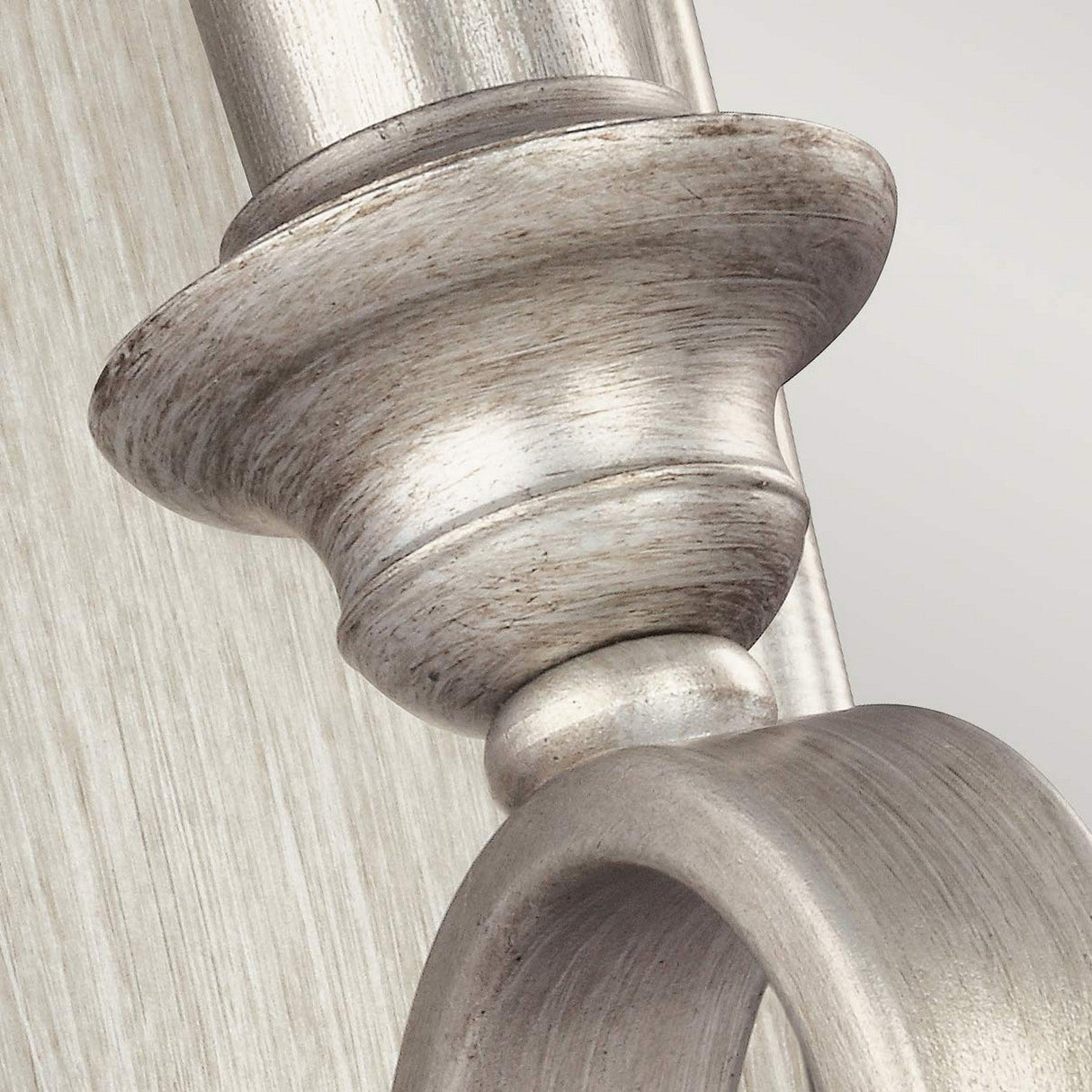 Close-up image of the DeWitt 1 Light Wall Light in French Provincial style, showcasing a rounded top with a circular base, mounted on a textured vertical surface. The finish is Sunrise Silver against a light background.