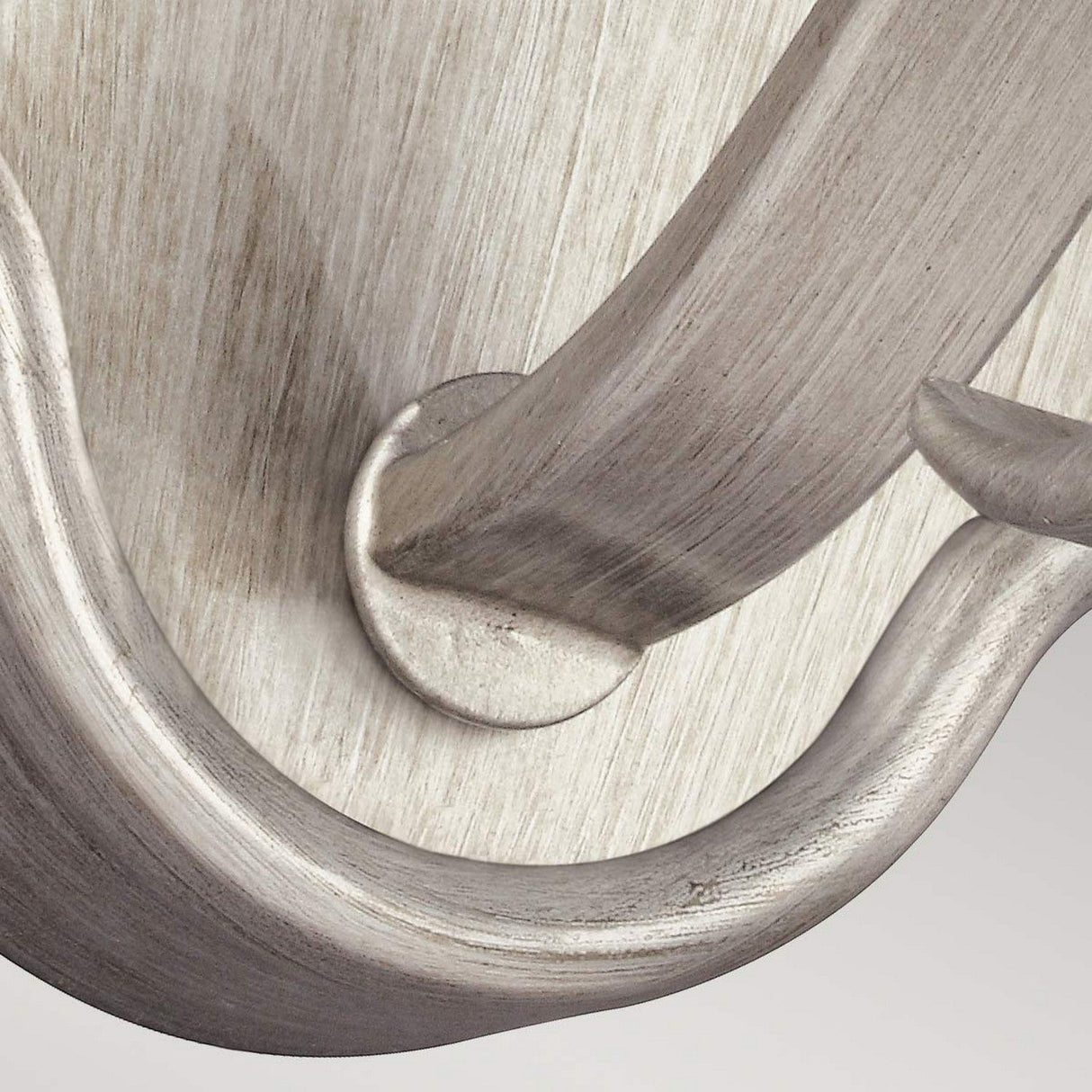 Close-up of a metallic, curved design featuring the DeWitt 1 Light Wall Light in a Sunrise Silver finish. The image showcases smooth, overlapping arcs and an elegant, polished texture, suggesting part of a decorative object or furniture piece in the French Provincial style.