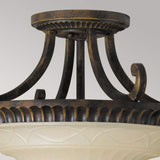 The Drawing-2 Room 2 Light Semi Flush in Walnut showcases an ornate ceiling light fixture with a bronze and walnut finish, featuring decorative scrollwork reminiscent of Edwardian design. It includes a frosted glass dome embellished with an elegant carved pattern.