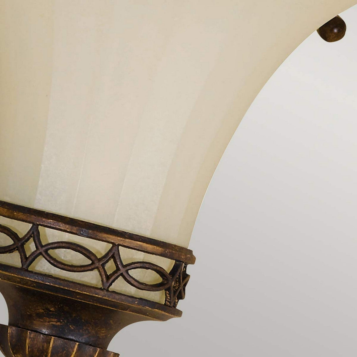 Close-up of the Drawing-3 Room 1 Light Wall Uplighter from the Drawing Room collection, featuring an ornate metal fixture with circular motifs and a walnut finish, reminiscent of Edwardian style. The frosted glass shade highlights the upper section of the lamp against a neutral background.