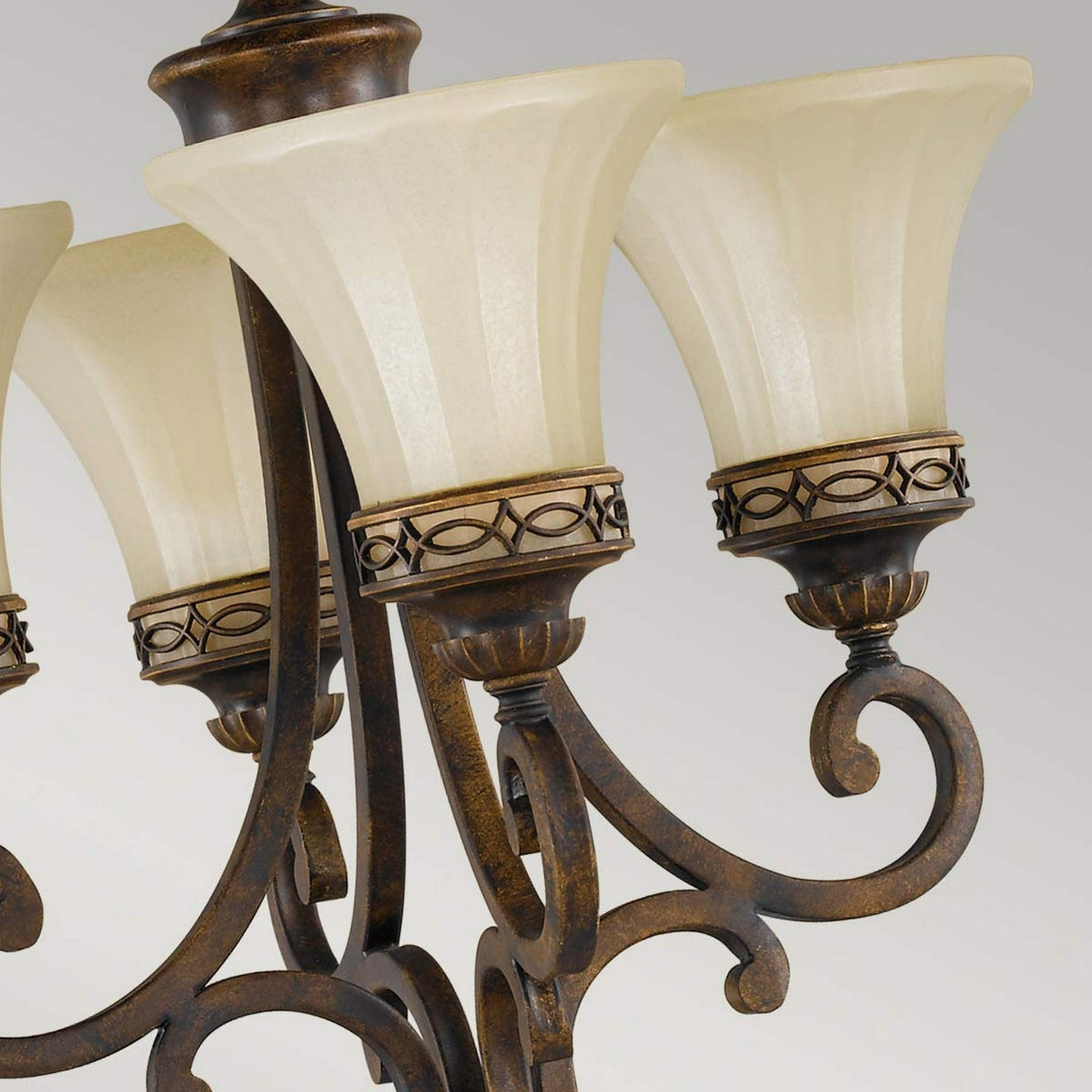 Close-up of the Drawing 4 Light Chandelier - Walnut, showcasing its ornate design with a bronze finish and cream-colored glass shades that reflect Edwardian tradition. The chandelier features intricate scrollwork and decorative metal bands around the base of each shade, evoking a timeless elegance reminiscent of a refined walnut finish.