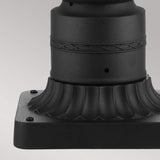 Detailed focus on a black metal base with intricate decorative elements, displaying a fluted design along with an engraved band. It is mounted on a square platform secured by four small bolts at each corner. This design pairs beautifully with the English Bridle 3 Light Outdoor Medium Pedestal in black finish to highlight its elegance.