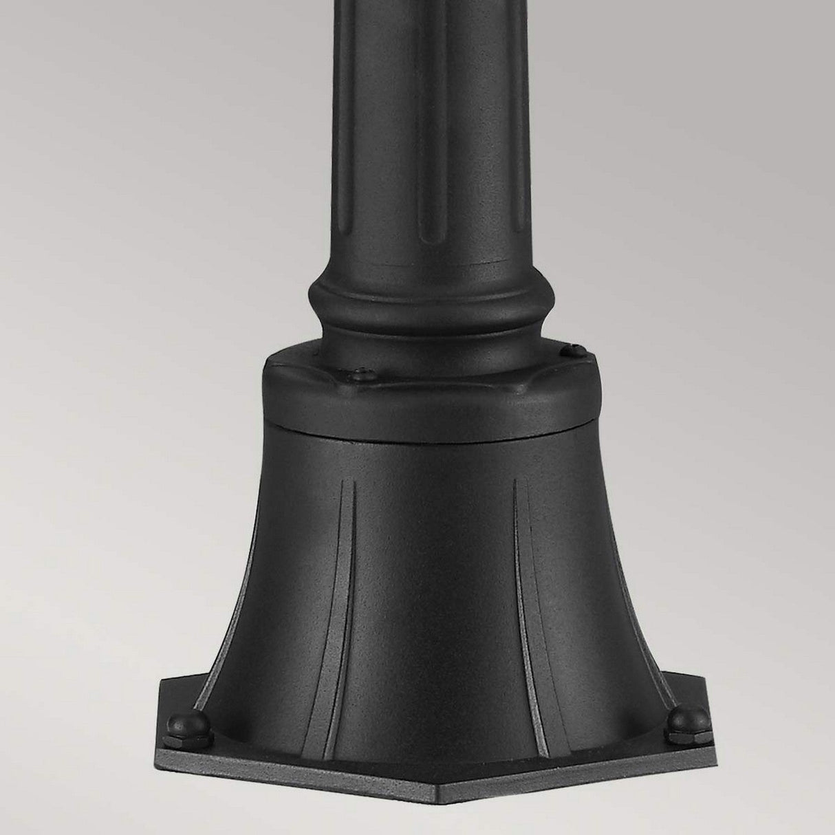 A close-up of a decorative black lamp post base highlights its sturdy, hexagonal structure with subtle grooves and rivet details. Its classic design wonderfully complements the English Bridle 3 Light Outdoor Medium Pillar - Black style against a plain gray background.