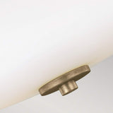 A detailed view of the Evington 2 Light Semi Flush in gold showcases a circular metallic fastener in a sunset gold finish, which secures a frosted glass shade. The fastener is centrally positioned at the bottom, offering an elegant contrast to the sleek, white surface of the blown opal etched glass.