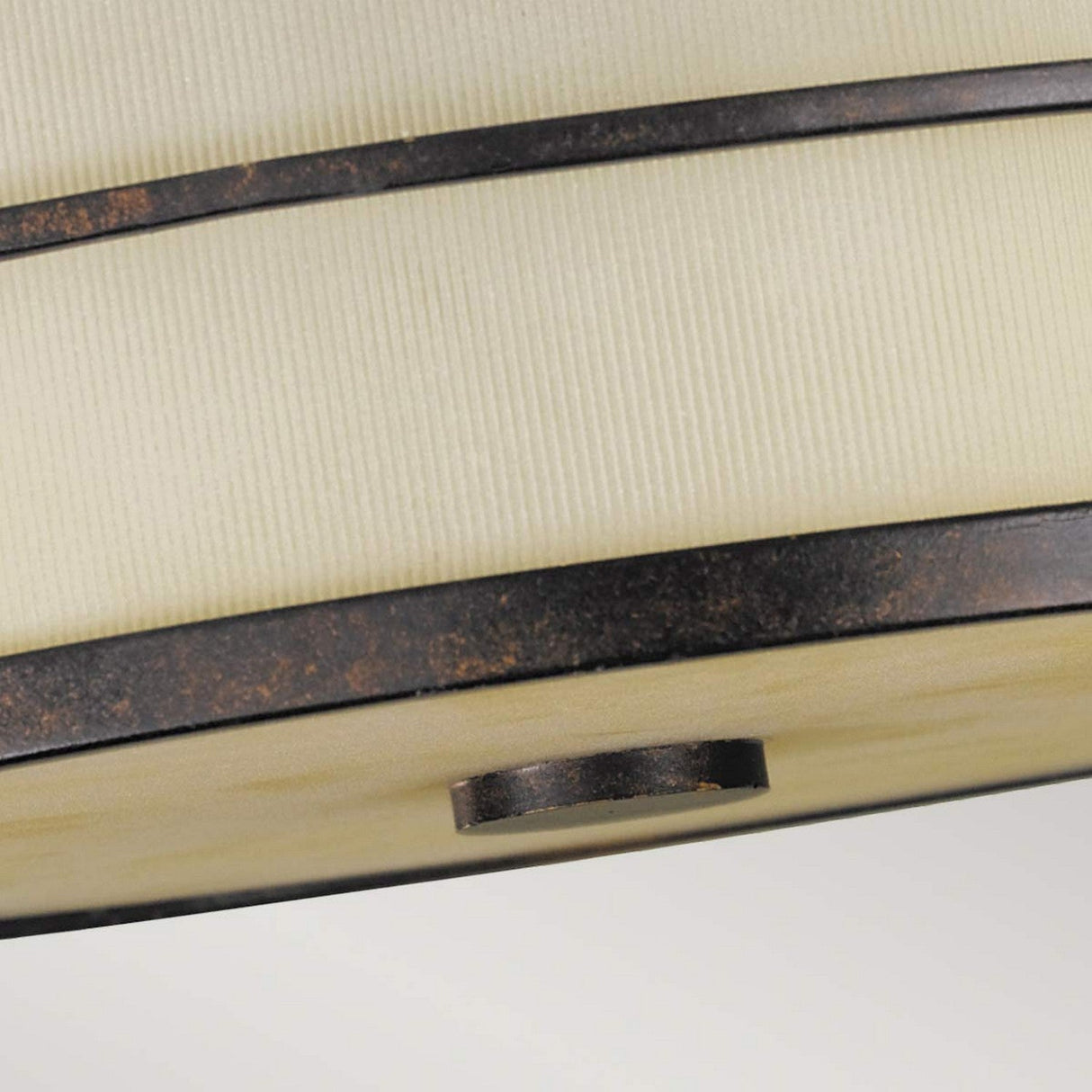 Close-up of the beige fabric lampshade with subtle vertical lines, bordered by two dark, textured metal bands characteristic of the Fusion 3 Light Semi Flush in Grecian Bronze.