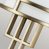 A detailed view of a metal architectural element with a geometric pattern highlights the sophistication of Painted Natural Brass. Rectangular shapes and bars in a gold finish stand out against a neutral gray background, presenting an exquisite contrast reminiscent of the Fusion 1 Light Wall Light, featuring its ribbed opal glass shade.