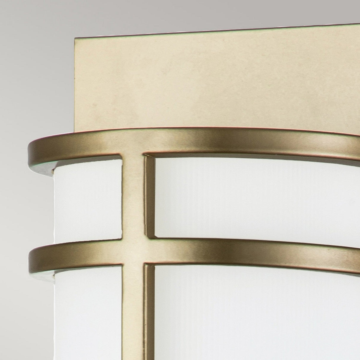 Close-up of the Fusion 2 Wall Light in painted natural brass. This fixture features opal glass shades with a geometric brass overlay, resulting in a sleek and elegant design. The background is a neutral, light gray color.