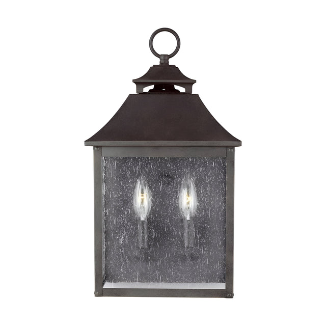 The Galena 2 Light Outdoor Half Lantern in Grey features a vintage-style design with a dark metal frame and clear glass pane. This outdoor half lantern accommodates two candle-like bulbs, offering classic elegance, and includes a loop at the top for convenient hanging—perfect for sophisticated exterior lighting.