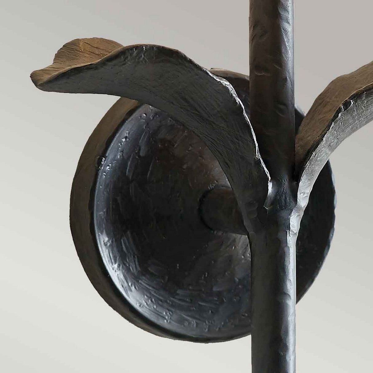 Close-up of the Georgia 1 Light Wall Light, a beautifully crafted sconce featuring leaf-like details. The fixture showcases an aged iron finish and is set against a plain background, complemented by a white cotton shade.