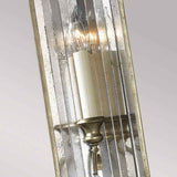 Close-up of the Gianna 1 Light Wall Light, featuring a candle-like bulb encased in ribbed, reflective glass. Its gilded silver finish adds a classic and elegant touch to the design, exuding a vintage charm reminiscent of Italian interiors.